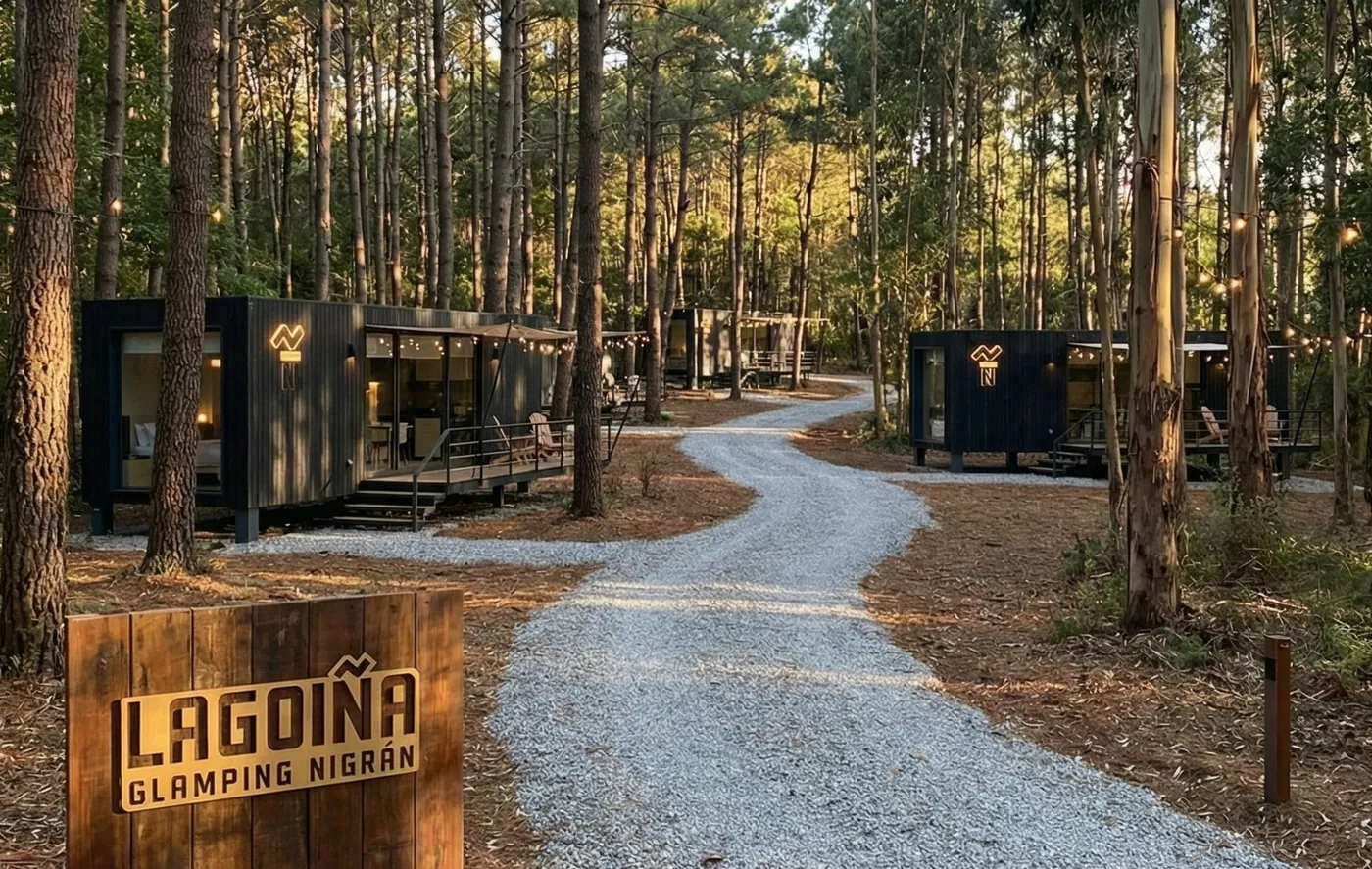 Camino de grava entre pinos hacia las suites, con el cartel de madera de Lagoiña