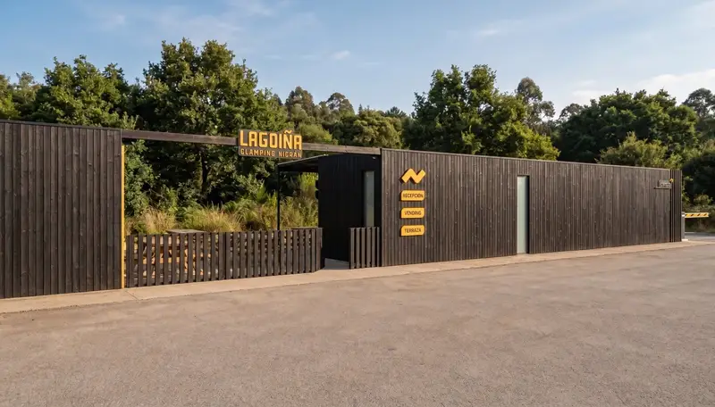 La entrada a Lagoiña Glamping, con el portón abierto entre el cerramiento de listones oscuros