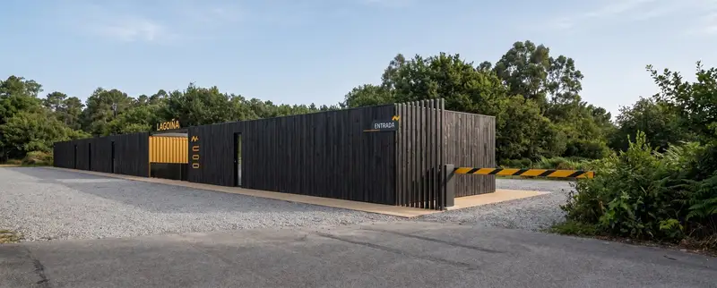 El cerramiento de listones de madera oscura que da fachada a Lagoiña desde la carretera